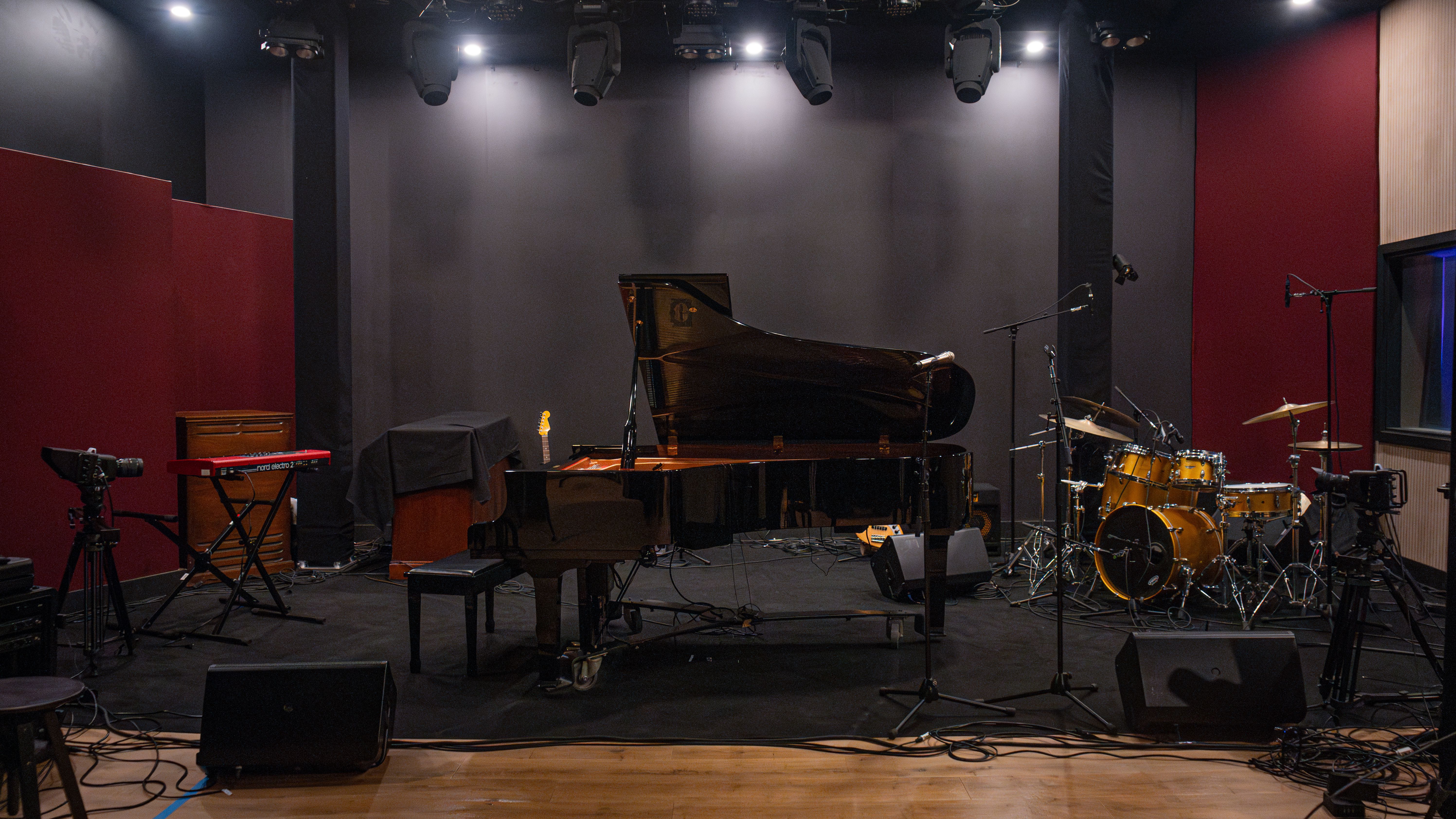 Live room with grand piano, drums, and full backline